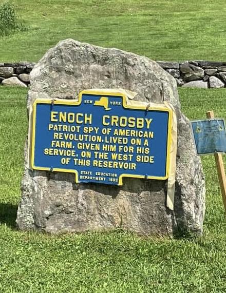 Blue and yellow New York State historic marker reading ENOCH CROSBY. Patriot spy of the American Revolution. Was associated with Carmel. His farm was nearby and he is buried at Gilead. One mile from here. State Education Department 1932.
