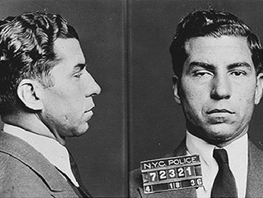Black-and-white double police photograph, profile and full face, of a dark-haired man in a suit and tie with a scarred right eyelid. The board across his chest reads &lsquo;N.Y.C. POLICE 72321&rsquo; with the date 4 18 36.