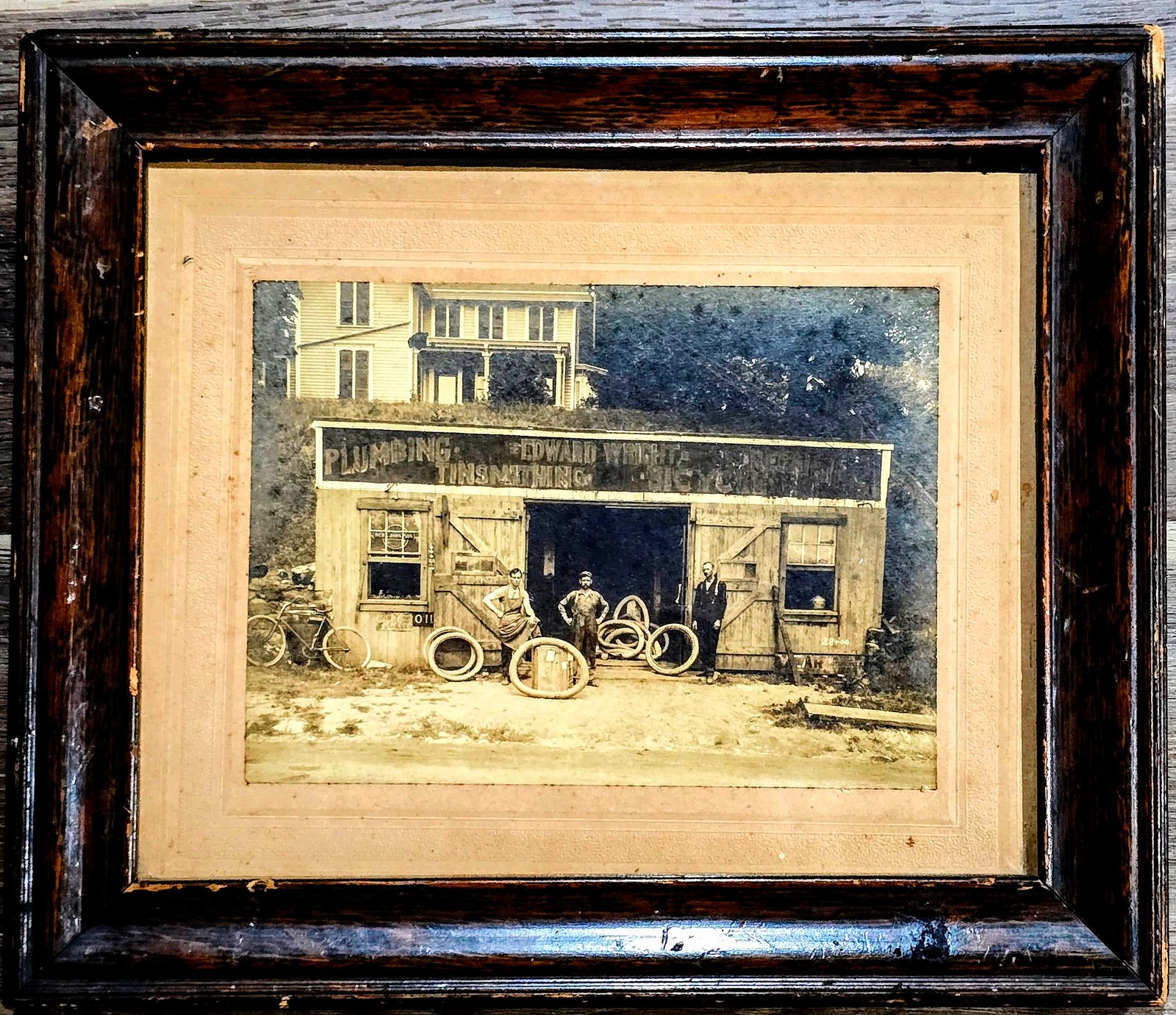 The shop photograph in a dark oak frame with an embossed cream mat, the wood worn at the corners.