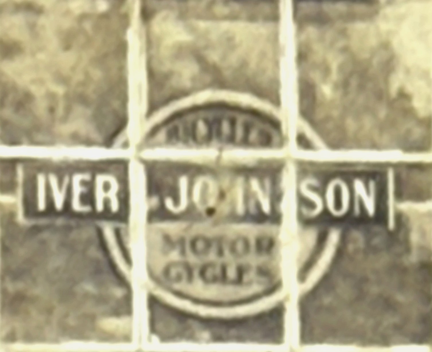 Close crop of a window pane bearing a circular Iver Johnson Motor Cycles dealer emblem.